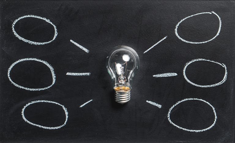 A lightbulb on a chalkboard symbolizes creativity, innovation, and ideas.